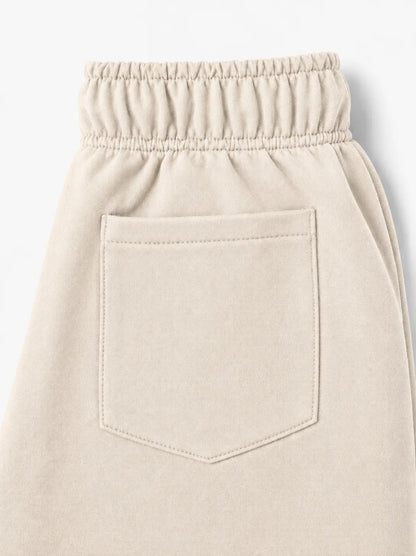 Close-up of a light beige or cream-colored garment, showing an elastic waistband and a single front patch